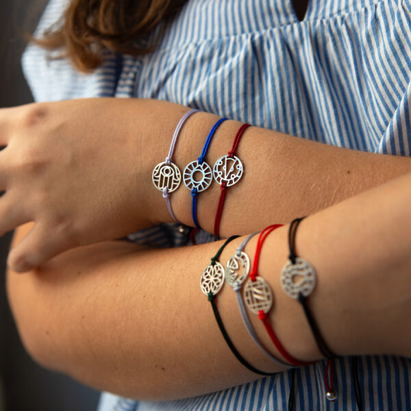 Modelo com os 7 motivos da pulseira da sorte da coleção good luck da Leitão & Irmão. Mão de Fátima, olho turco, joaninha, trevo, andorinha, sete e ferradura.
