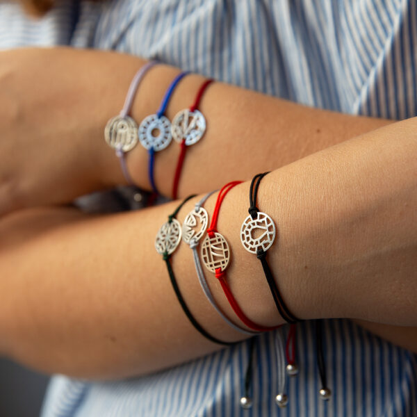 Modelo com os 7 motivos da pulseira da sorte da coleção good luck da Leitão & Irmão. Mão de Fátima, olho turco, joaninha, trevo, andorinha, sete e ferradura.